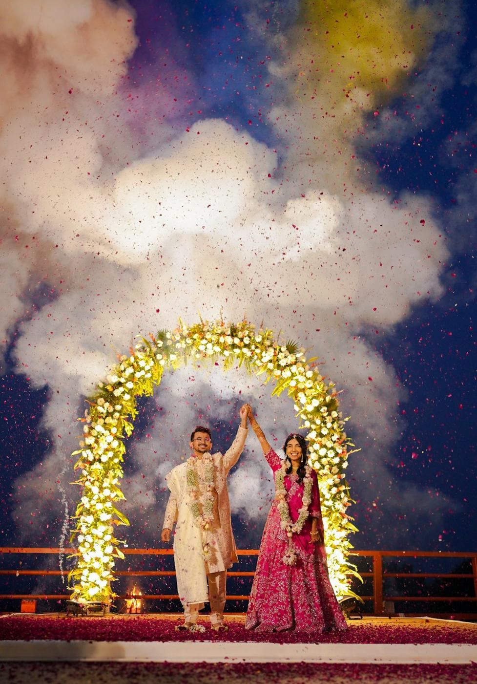Couple under a floral arch with confetti